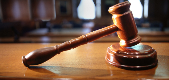 A wooden judge's gavel and block on a desk.